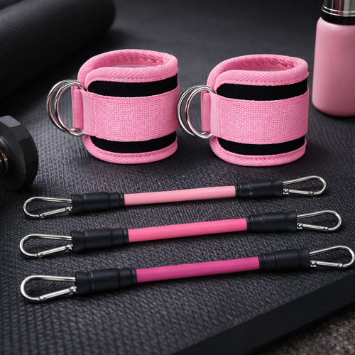 Paire de chevillères de fitness roses rembourrées avec mousquetons et bandes élastiques assorties sur un tapis de sport.